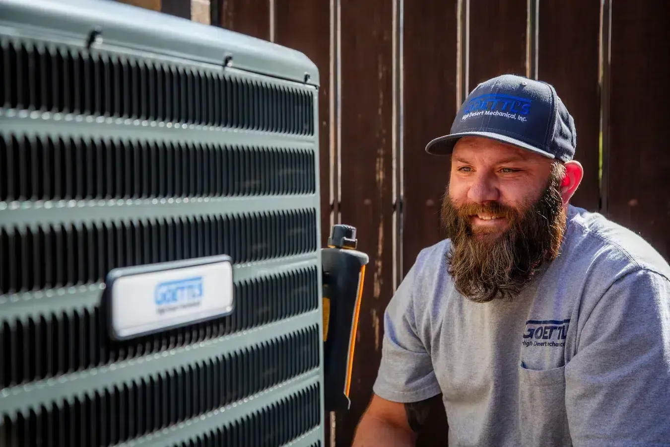Goettl’s High Desert Mechanical technician performing inspection beside outdoor condenser unit – Prescott Valley AZ