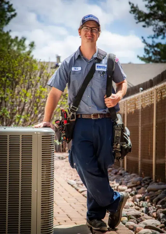 Goettl’s High Desert Mechanical technician walking toward condenser unit carrying tools – Prescott Valley AZ