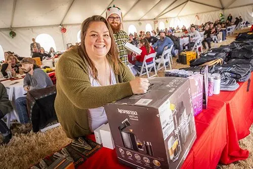 Smiling woman holding a gift box during indoor holiday or community giveaway – Goettl’s High Desert Mechanical Prescott Valley AZ