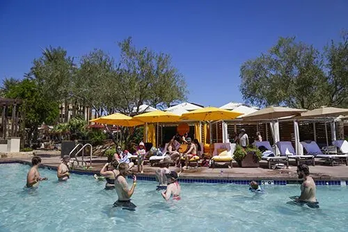 Families relaxing in a resort-style pool under yellow umbrellas during company event – Goettl’s High Desert Mechanical Prescott Valley AZ
