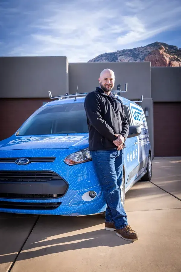 Goettl’s High Desert Mechanical technician standing beside compact service vehicle with mountains behind – Prescott Valley AZ