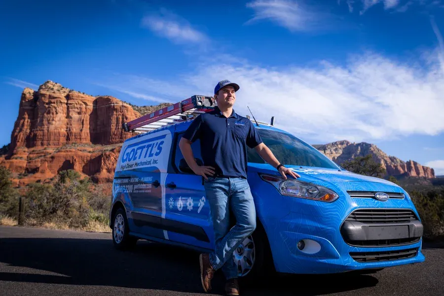Goettl’s High Desert Mechanical technician leaning on service van in red rock landscape – Prescott Valley AZ