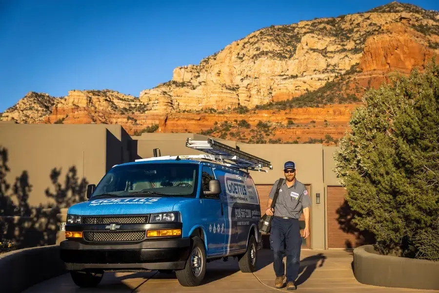 Goettl’s High Desert Mechanical technician standing beside service truck in front of desert-style home – Prescott Valley AZ
