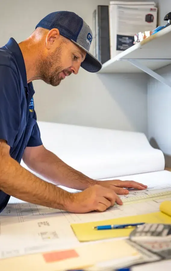 Technician measuring and marking plans at workbench – Goettl’s High Desert Mechanical Prescott Valley AZ
