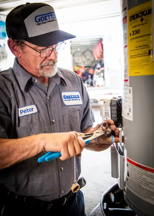Goettl’s High Desert Mechanical technician adjusting water heater piping with pliers – Prescott Valley AZ