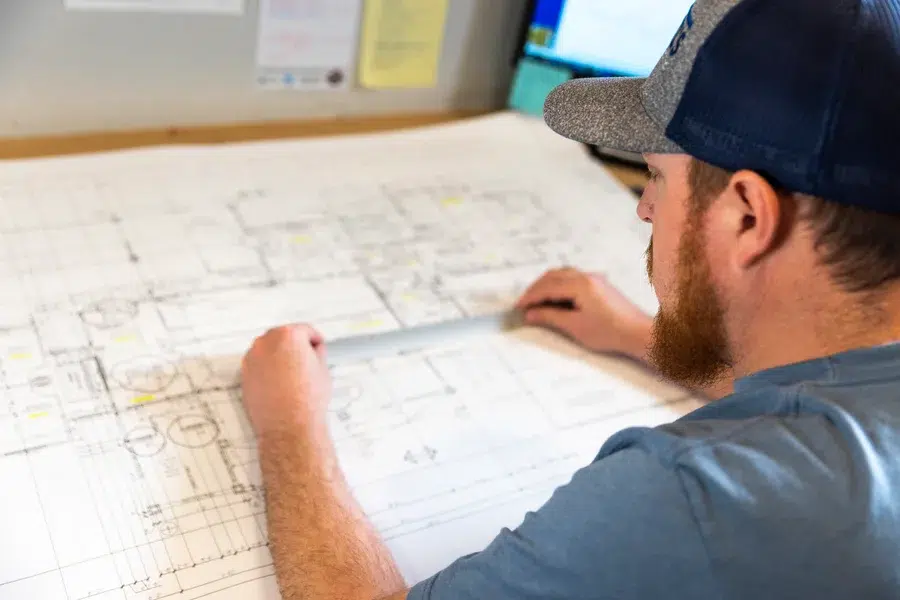 Technician studying large system layout on blueprint during project planning – Goettl’s High Desert Mechanical Prescott Valley AZ