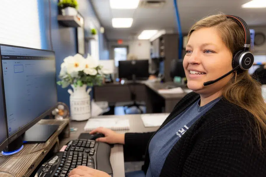 Customer service representative smiling at desk while handling calls – Goettl’s High Desert Mechanical Prescott Valley AZ