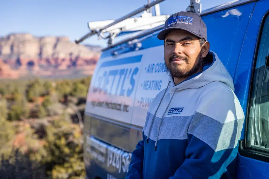 Goettl’s High Desert Mechanical technician standing beside service van with red rock cliffs behind – Prescott Valley AZ