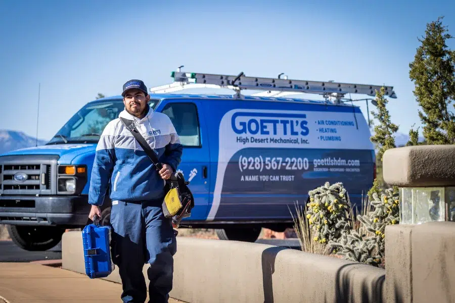 Goettl’s High Desert Mechanical technician carrying tool bag beside service van in desert neighborhood – Prescott Valley AZ