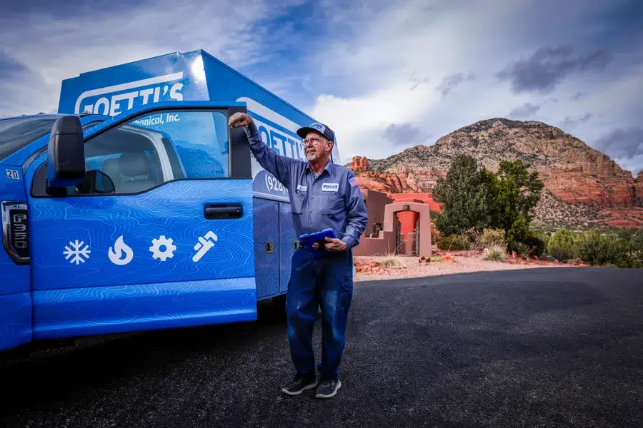 Goettl's technician next to service truck, Arizona mountains behind