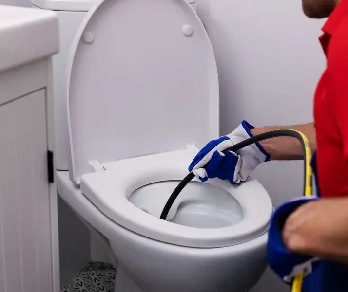 Plumber unclogging blocked toilet with hydro jetting