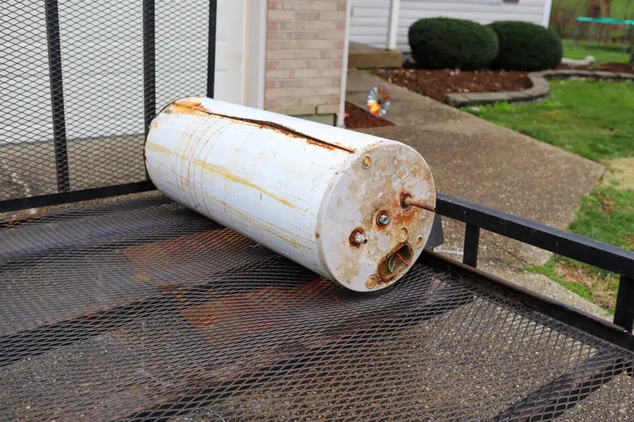 An old and broken hot water heater being taking away on a trailer in front of a home – Prescott Valley AZ