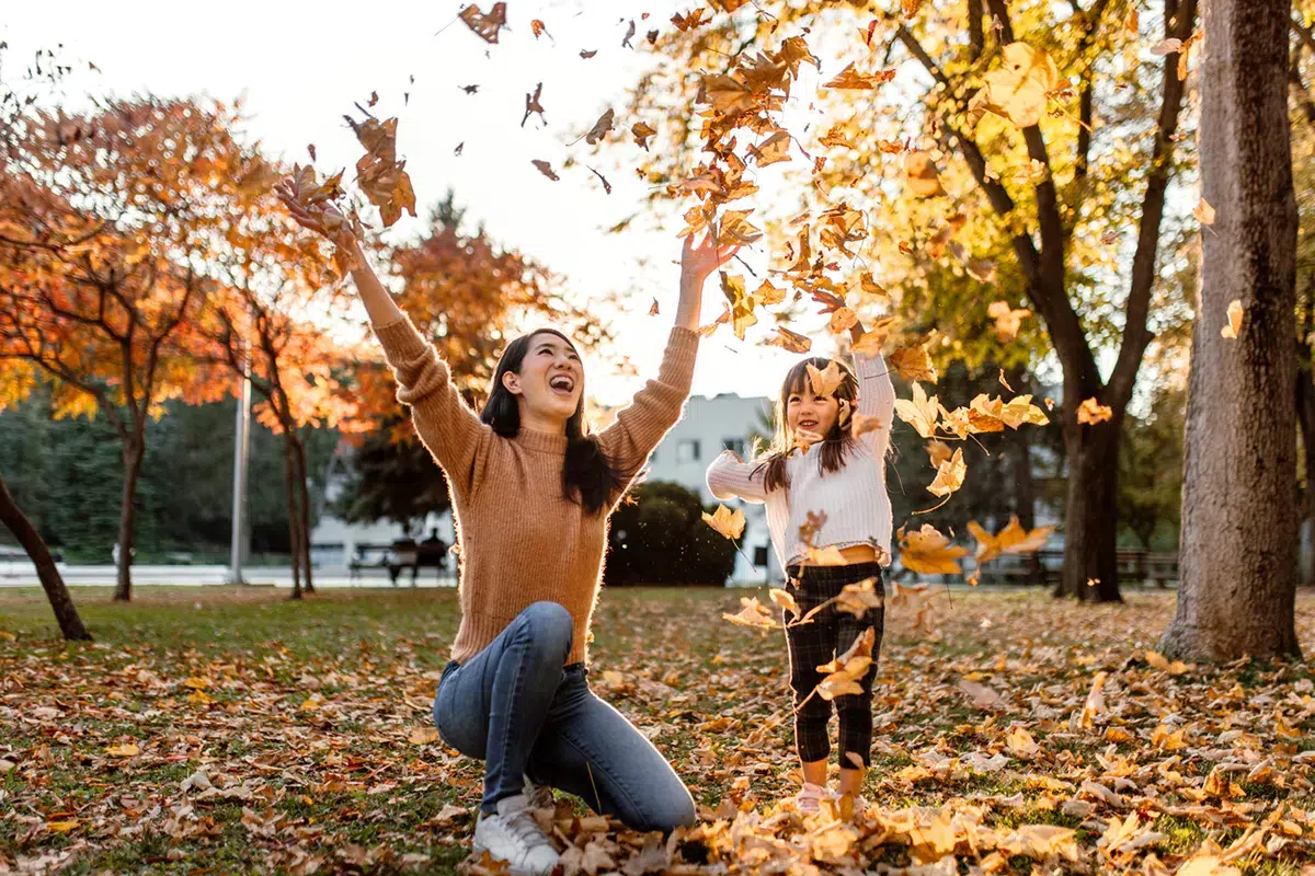 Woman happy with daughter in fall leaves