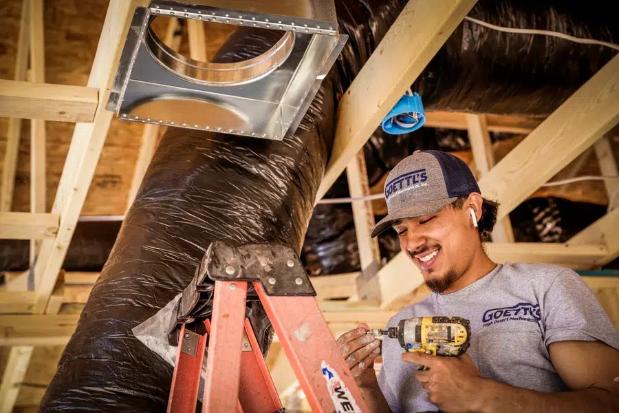 Technician securing ductwork and fittings from ladder during install – Goettl’s High Desert Mechanical Prescott Valley AZ