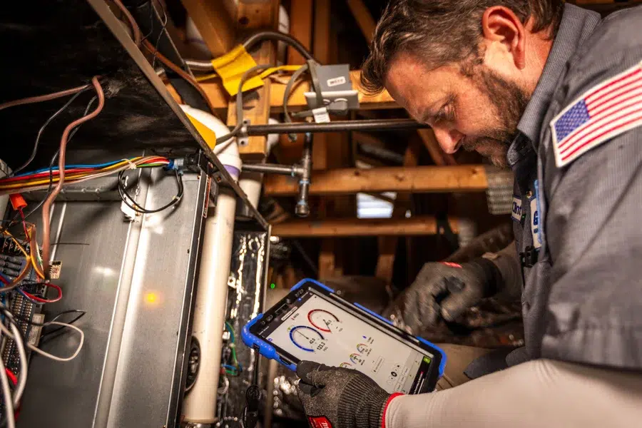 Goettl’s High Desert Mechanical technician reviewing system data of HVAC system on tablet during maintenance – Prescott Valley AZ