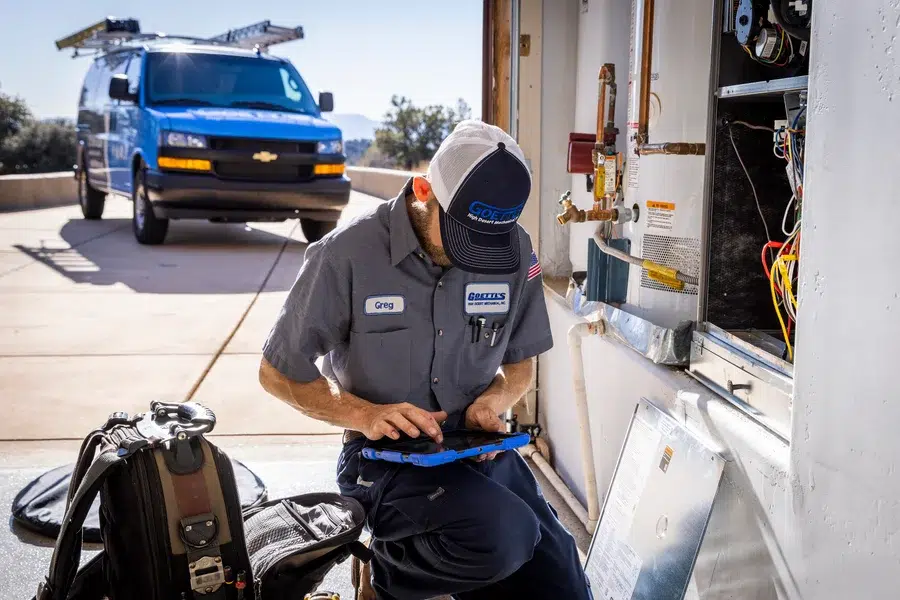 Goettl’s High Desert Mechanical technician reviewing HVAC system data on tablet during maintenance – Prescott Valley AZ