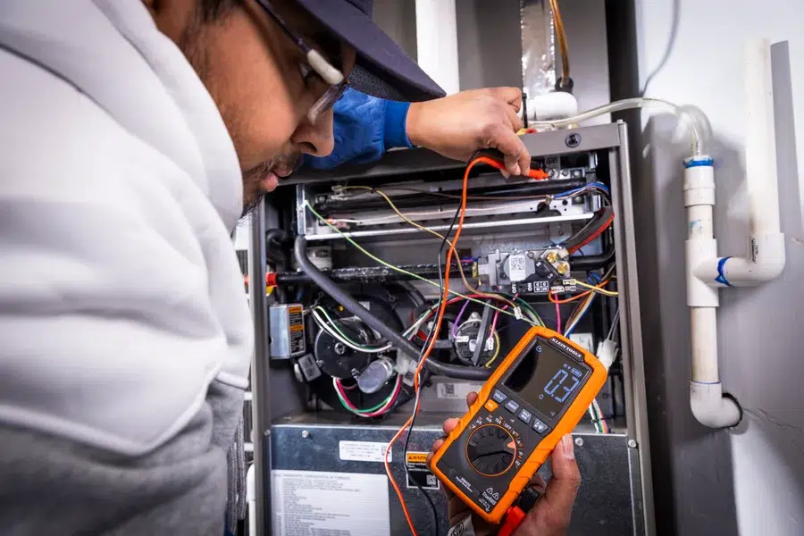 Goettl’s High Desert Mechanical technician testing furnace wiring with multimeter – Prescott Valley AZ